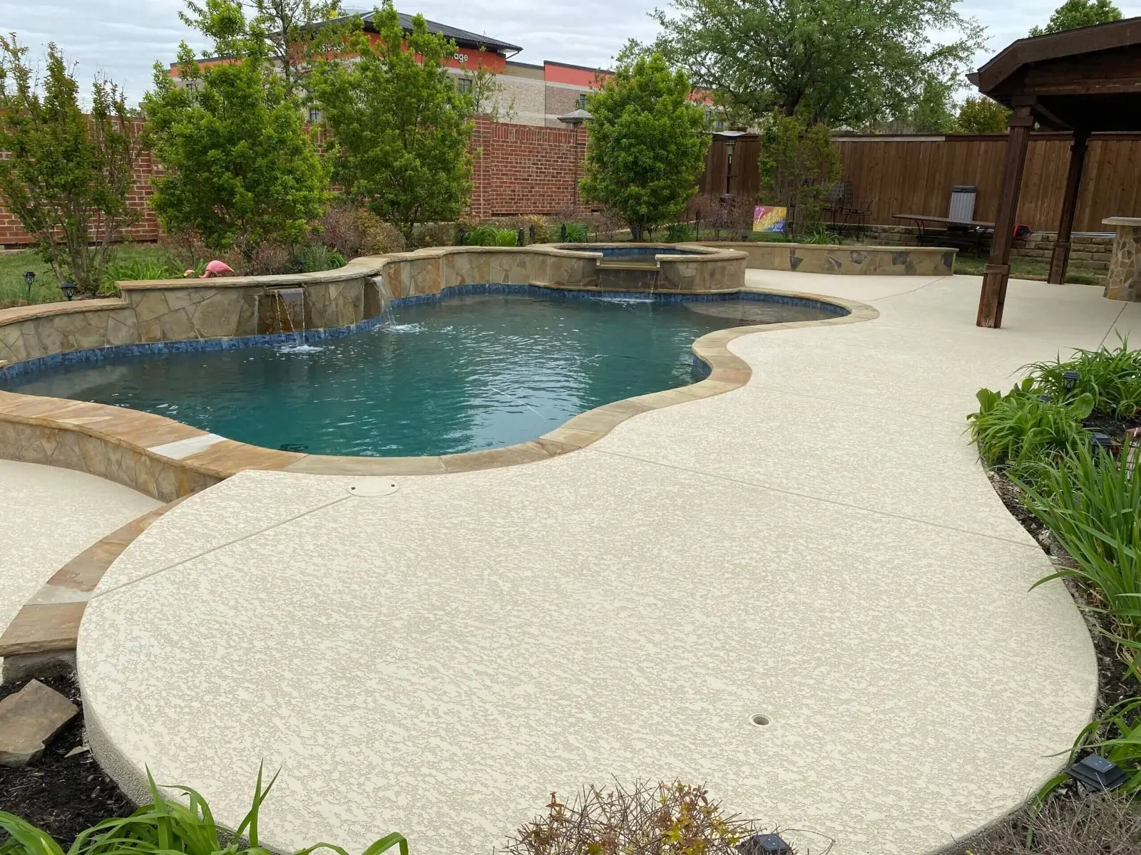Curved backyard pool with waterfall and pergola